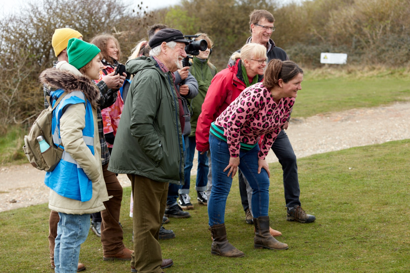 A group of residents reacting, with smiling faces, to plans for art installations as part of the Walk The Chalk project. Also visible is a videographer and a member of LYT Productions crew.